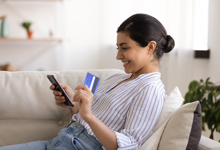 woman looking at her bank card and smartphone
